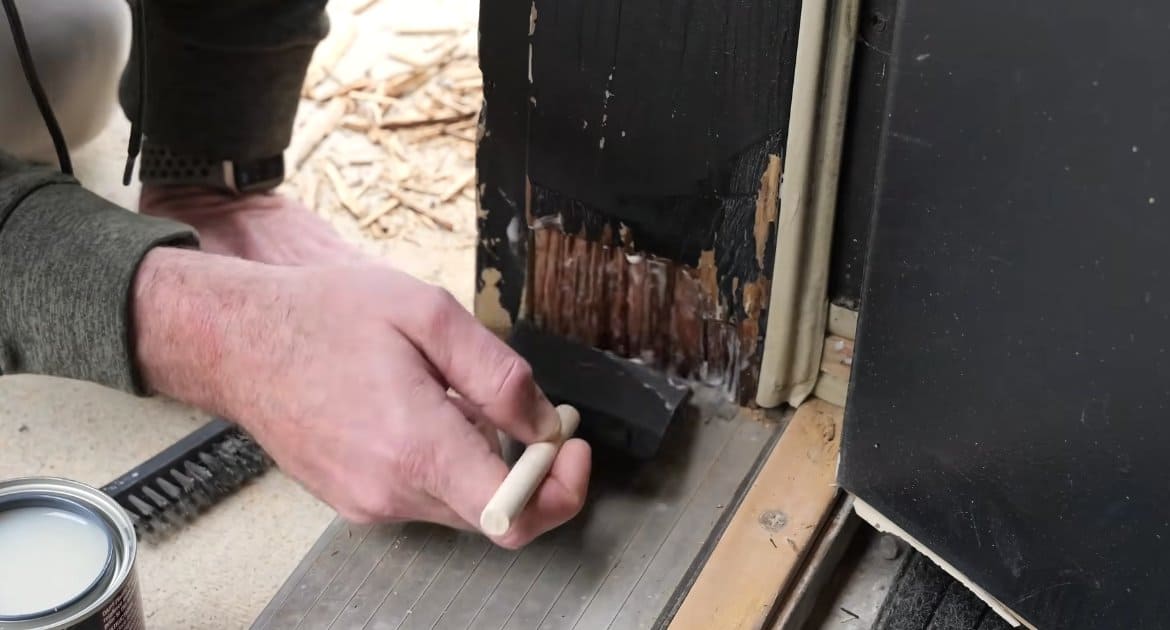 Brushing DAP Plastic Wood Rot Hardener onto a prepped, rotted door frame