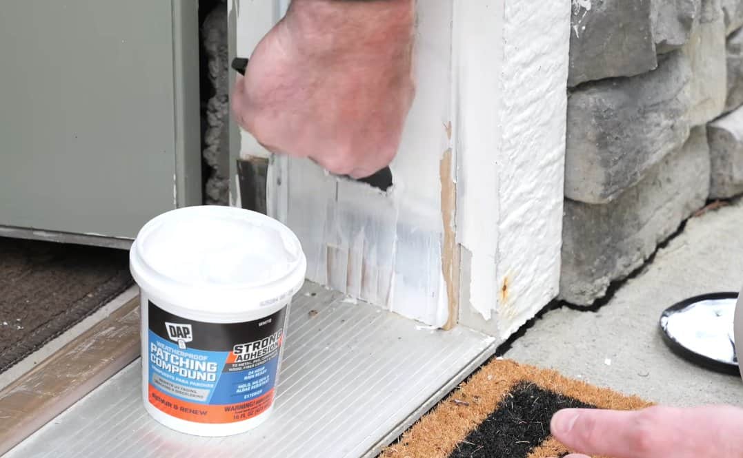 Applying DAP Weatherproof Patching Compound to early cracks on a second exterior door frame