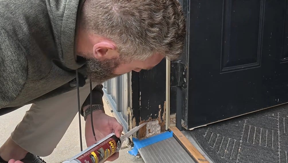 Dispensing DAP two-part Plastic Wood epoxy filler into a cleaned-out rotted door frame