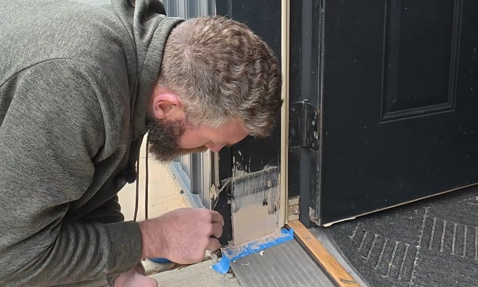 Smoothing and shaping DAP Plastic Wood epoxy filler with a putty knife inside the door frame repair
