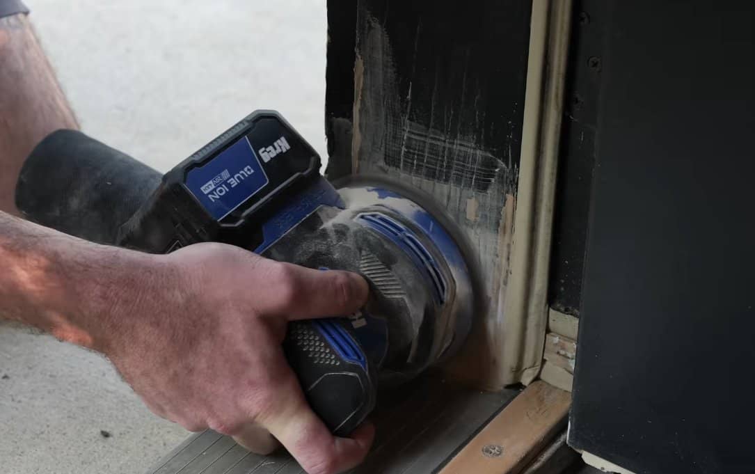Sanding the cured DAP epoxy filler flush with the surrounding door frame