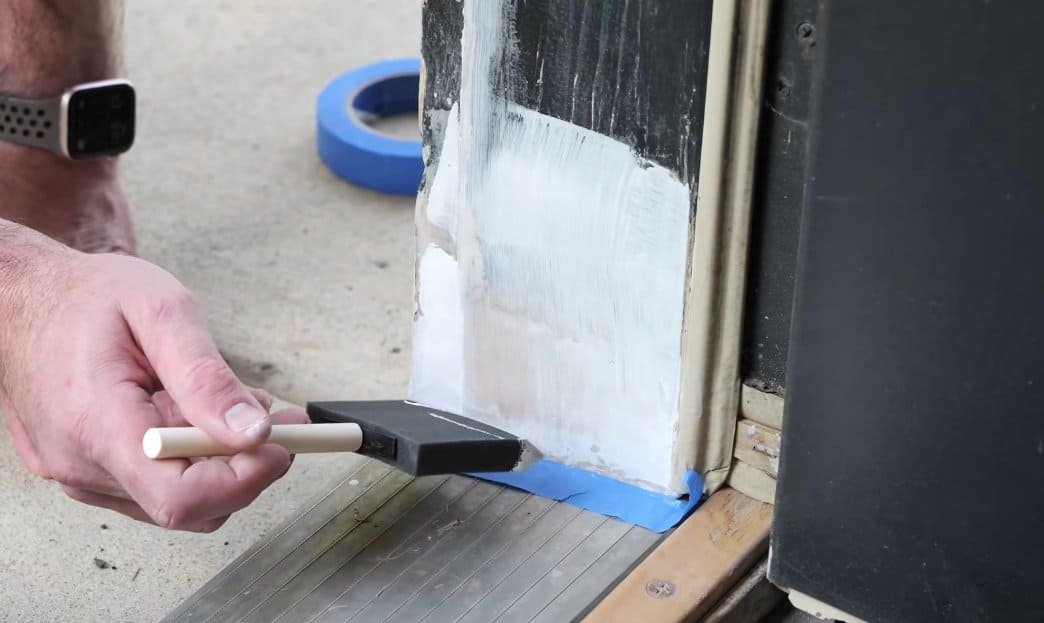 Applying exterior primer to a sanded and patched door frame repair