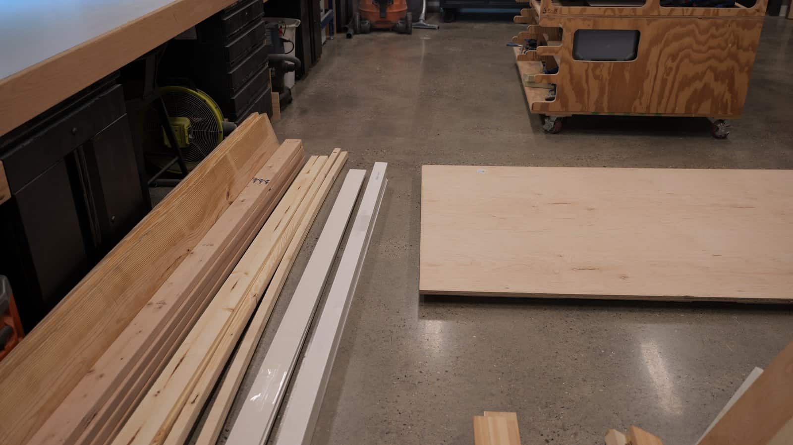Plywood and lumber for the bed frame laid out on the shop floor