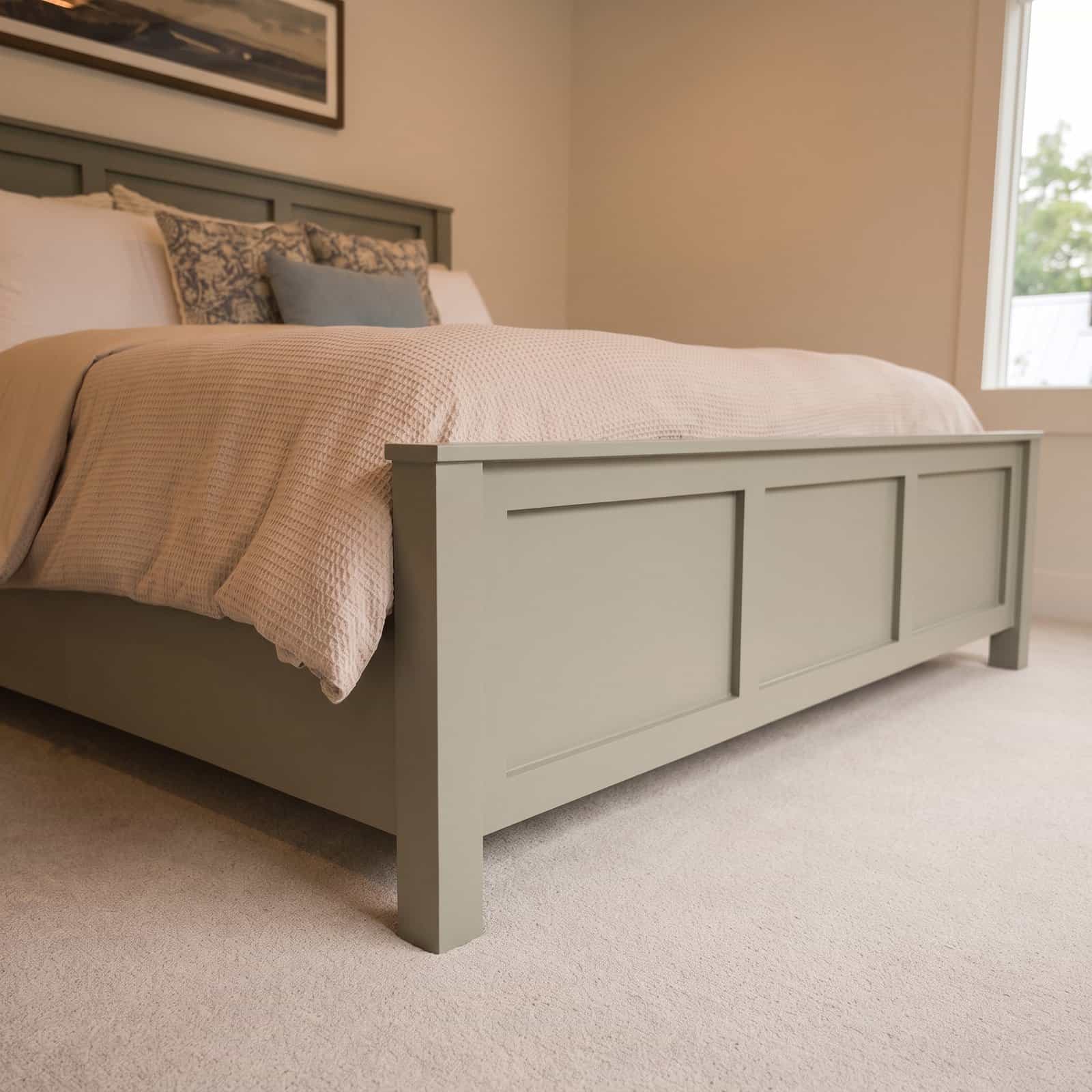 Low angle view of the DIY bed frame footboard with its three recessed panels and 1x4 cap