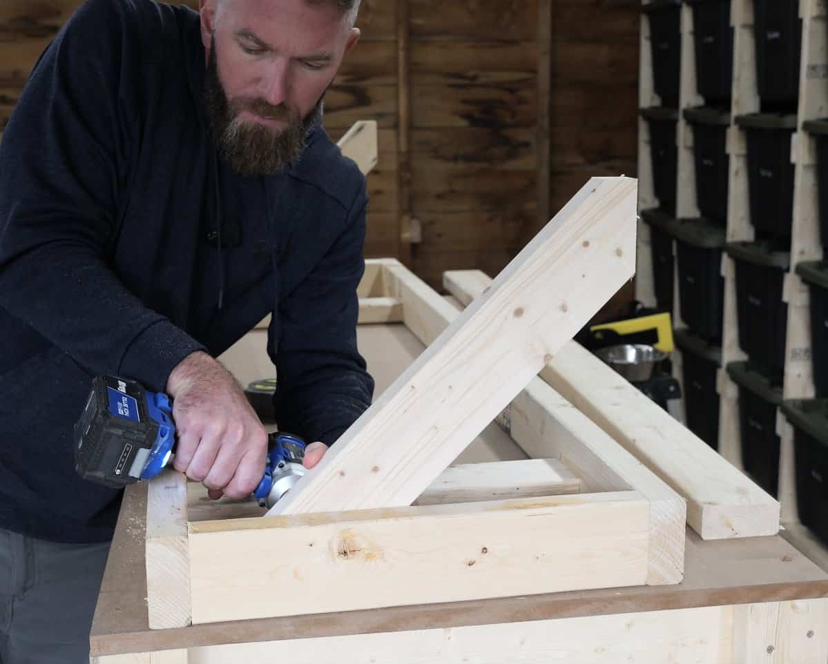 Screwing a 45 degree angled 2x4 support inside the end cross piece of the shelf frame