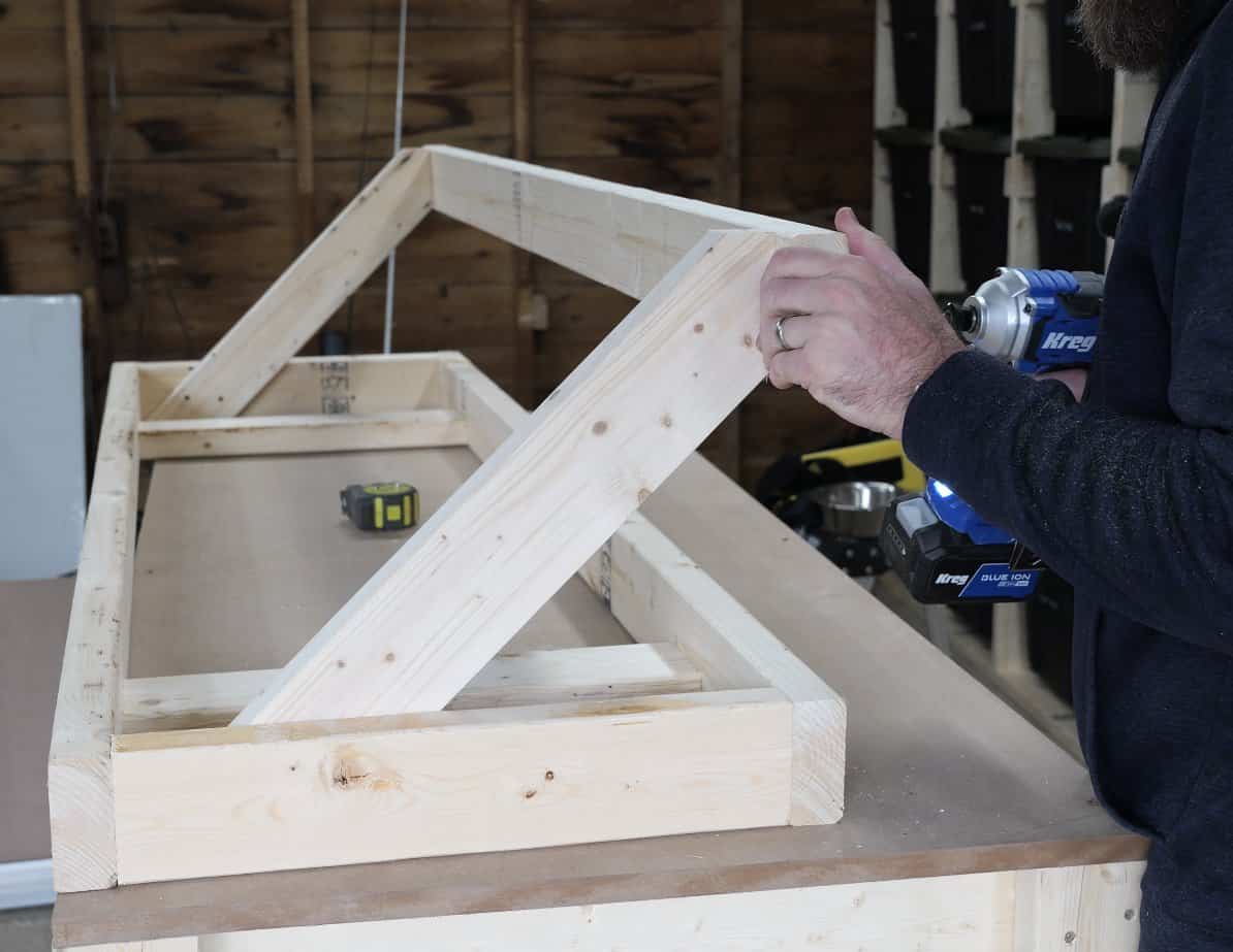 Garage shelf upside down on the bench with both angled supports and the bottom ledger attached