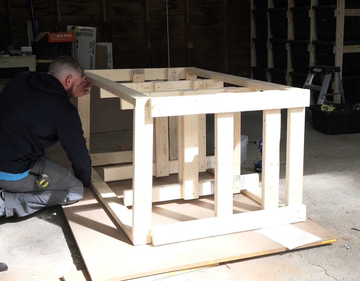 Standing the ladders between the top and bottom frames to assemble the workbench frame