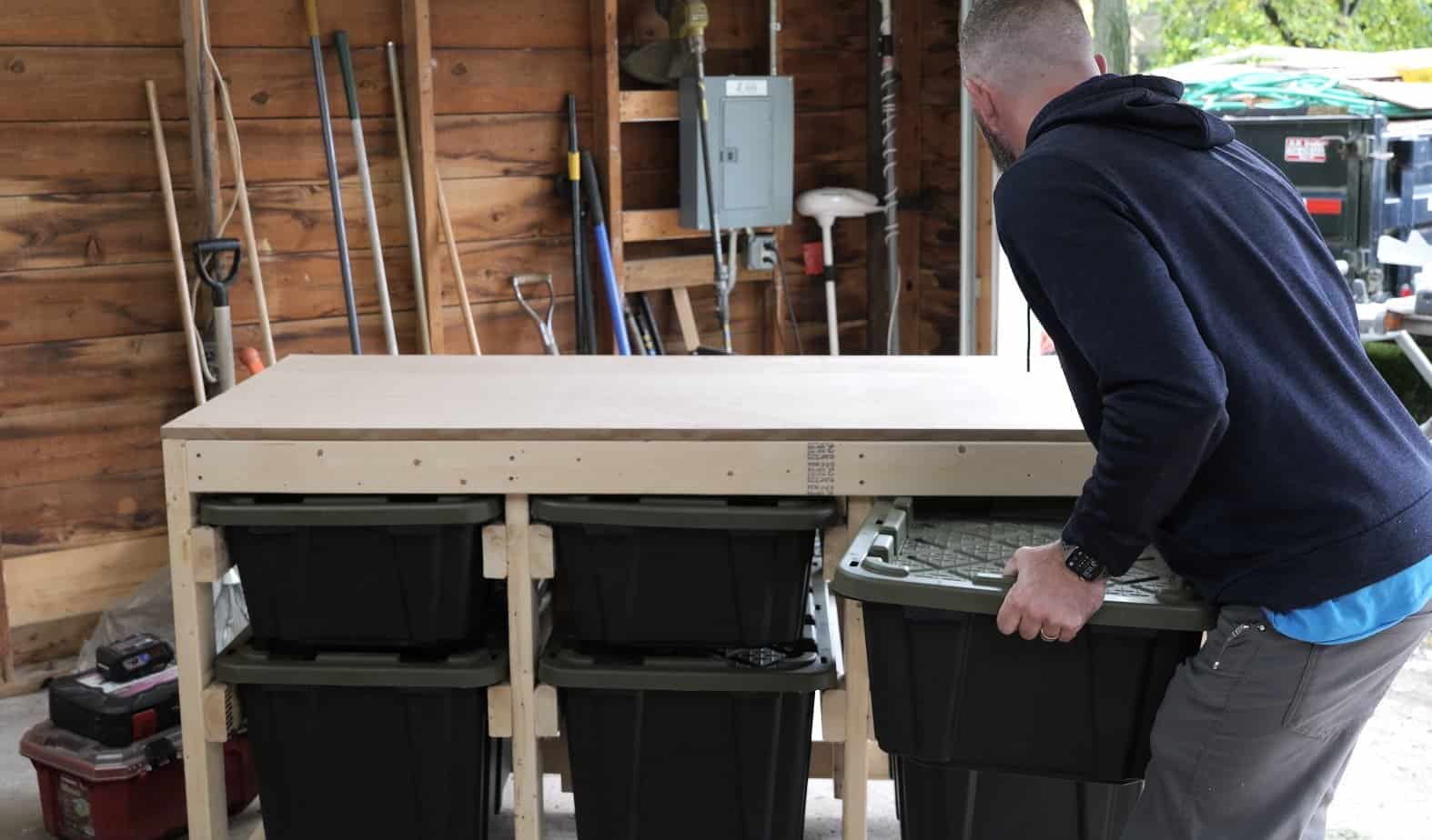 Sliding a 27 gallon tote onto its runners under the mobile workbench
