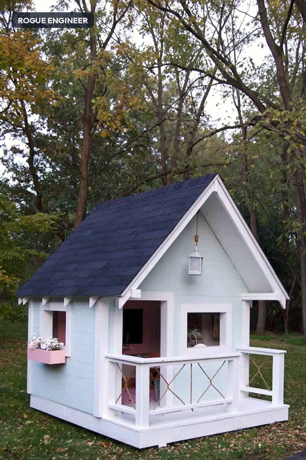 DIY playhouse plans: a backyard playhouse on an 8 foot deck with a covered porch, three windows and a steep shingled roof. Built on skids, sized for kids.