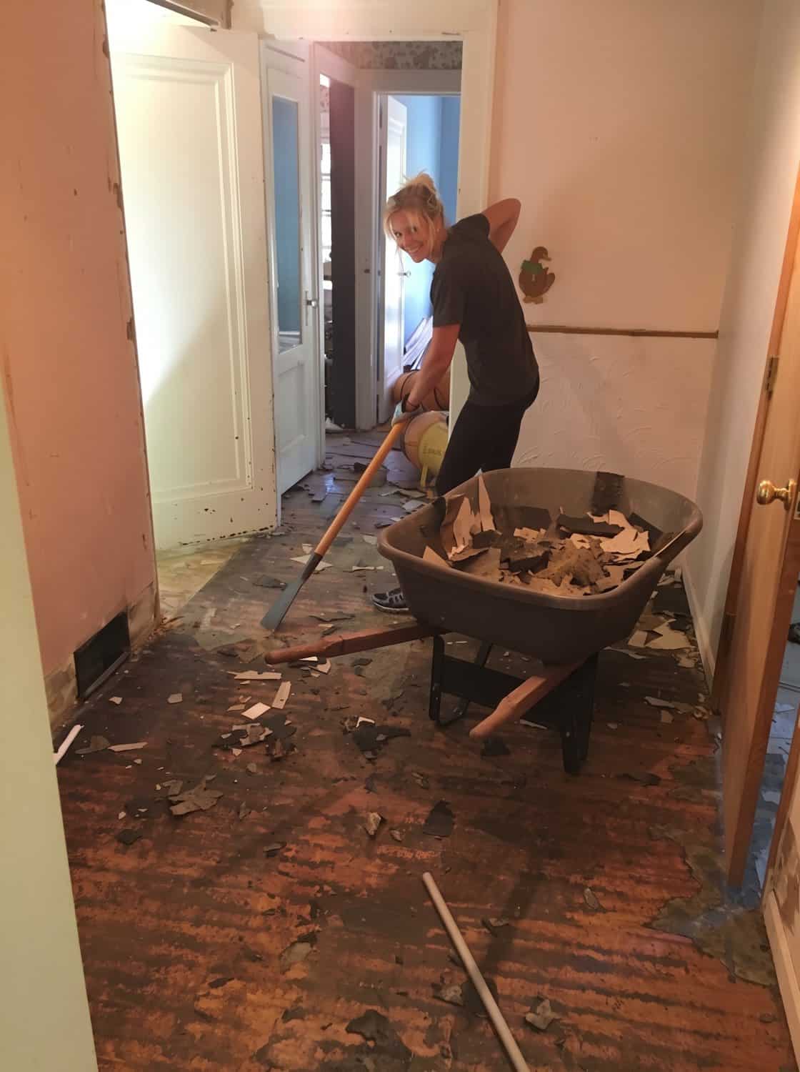 Scraping up linoleum and backing during tear-out in the renovation house
