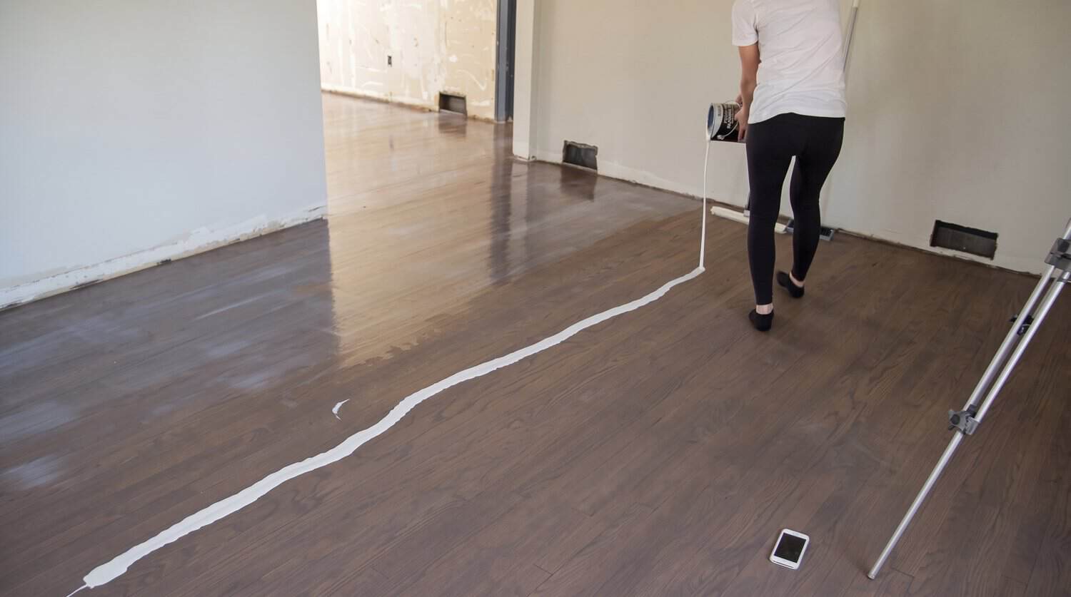 Pouring a ribbon of floor finish across the room